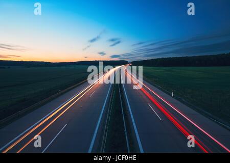 Alba sull'autostrada nel mezzo della campagna. Trasporto e vetture tema. Foto Stock