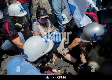 Caracas, Venezuela. 14 Giugno, 2017. Volontari la fornitura del primo aiuto durante le proteste contro il governo aiuta una donna malata, a Caracas, Venezuela, 14 giugno 2017. Il gruppo indossa caschi bianco con una croce verde. Così come un gruppo dall'Università Centrale di Caracas, altri piccoli gruppi che forniscono il primo aiuto hanno anche formato. Foto: Manaure Quintero/dpa/Alamy Live News Foto Stock