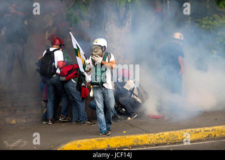 Caracas, Venezuela. 14 Giugno, 2017. Volontari provenienti da Università Centrale di Caracas che forniscono il primo aiuto durante le proteste contro il governo, a piedi da gas lacrimogeni durante una manifestazione di protesta a Caracas, Venezuela, 14 giugno 2017. Il gruppo indossa caschi bianco con una croce verde. Foto: Manaure Quintero/dpa/Alamy Live News Foto Stock