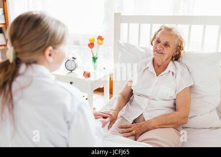 Fornire assistenza e supporto per anziani. Visita medico paziente anziano a casa. Foto Stock