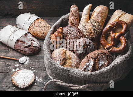 Delizioso pane fresco all'interno di un sacco su sfondo di legno Foto Stock