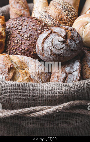 Delizioso pane fresco all'interno di un sacco su sfondo di legno Foto Stock