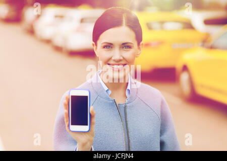 Donna sorridente che mostra smartphone tramite taxi in città Foto Stock