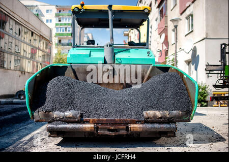 Industrial lastricatore di posa di asfalto fresco e bitume pavimentazione sulla parte superiore dello strato di ghiaia durante la costruzione di strade Foto Stock