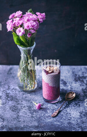 Succo di barbabietola budino di chia in un ripiano in vetro con marmellata di ciliege e un trito di noci del Brasile Foto Stock