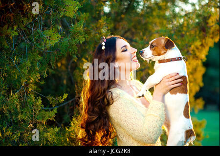 Felice giovane donna abbracciando e divertirsi con il suo Jack Russell Terrier all'aperto Foto Stock