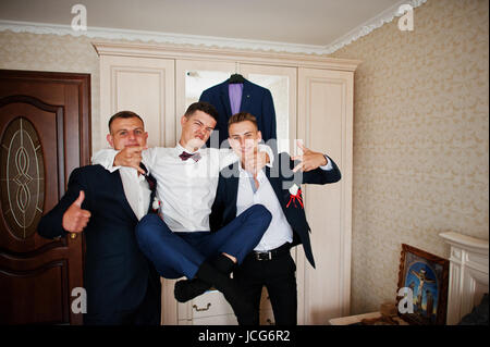 Bello lo sposo e groomsman in camera avvolgente accanto a specchio. Foto Stock