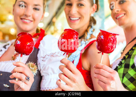 Amici in visita insieme fiera bavarese in costume nazionale eating Candy Apple Foto Stock