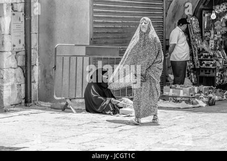 Donna seduta con un NIQAB, faccia un velo e una donna a piedi in un CHADOR, un tradizionale abito Muslem nel quartiere arabo,Città Vecchia di Gerusalemme, Israele. Foto Stock