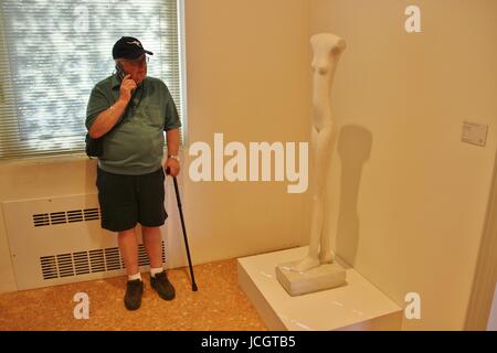 Alberto Giacometti la scultura Donna che cammina e un visitatore, ascoltando l'audio guida. Collezione Peggy Guggenheim di Venezia, Italia, Europa. Foto Stock