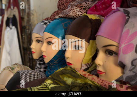 Una linea di capi in plastica modellazione il velo o hijabs siede su un tavolo in un piccolo negozio di Fez, in Marocco. Foto Stock