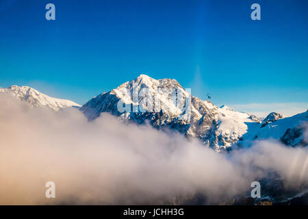 Un ampio panorama di montagne innevate con alcune nuvole intorno, Alpi del Sud situato nel South Island, in Nuova Zelanda. Foto Stock