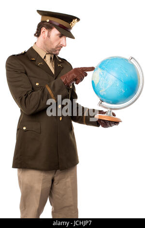 Giovane ufficiale militare azienda mappa del globo e indicante Foto Stock