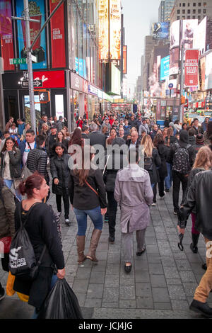 Le persone che attraversano le crosswalk pieno occupato il marciapiede di sera serata a Times Square a New York City USA Foto Stock