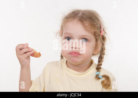 Bambina di tre anni con pig-tail e divertente con entusiasmo di mangiare un panino Foto Stock