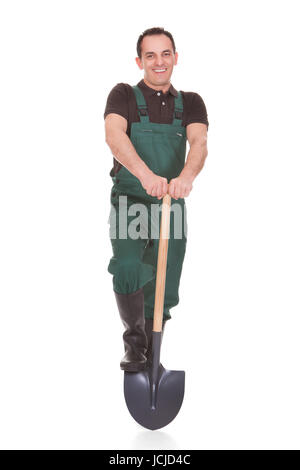 Felice LAVORATORE MASCHILE tenendo una pala su sfondo bianco Foto Stock