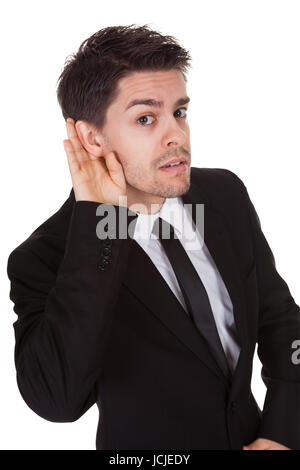 Imprenditore tenendo la mano al suo orecchio isolato su bianco Foto Stock