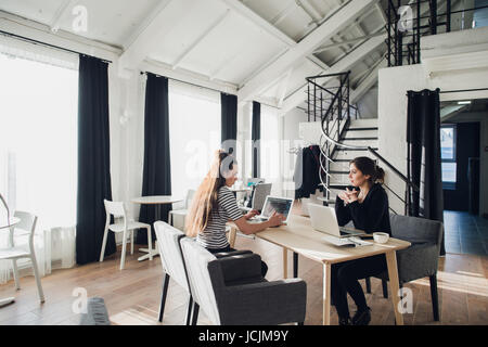 Giovane architetto studente intervistata per il lavoro nella società di design,conversazioni su avvio corretto concetto con tazza di tè in seduta coworking con wifi e laptop. Foto Stock