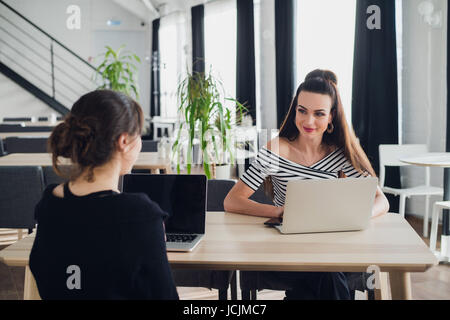 Giovane architetto studente intervistata per il lavoro nella società di design,conversazioni su avvio corretto concetto con tazza di tè in seduta coworking con wifi e laptop. Foto Stock