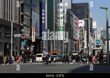 Strada trafficata scena a Tokyo in Giappone dove il traffico e i pedoni vie tor lo spazio in questa affollata capitale metropolitano in una giornata di sole. Foto Stock