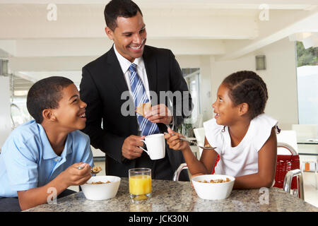 Padre di fare colazione con i bambini prima di lavorare Foto Stock