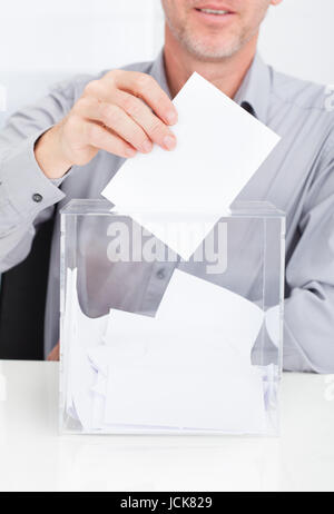 Close-up di persona l'inserimento di ballottaggio in scatola trasparente Foto Stock