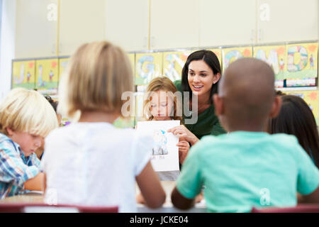 Pupilla elementari che mostra il disegno ai compagni in aula Foto Stock