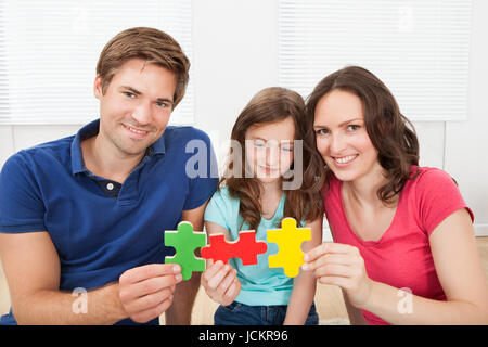 Ritratto di famiglia felice unire i pezzi del puzzle a casa Foto Stock