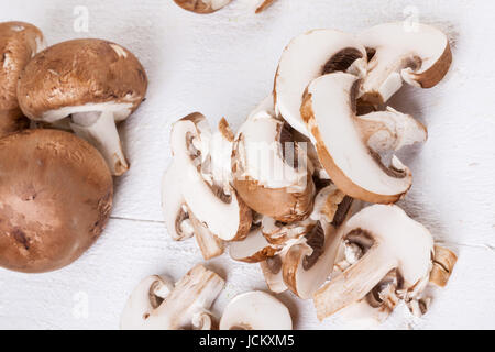 Frische Steinchampignons Champiggnons im ganzen und in Scheiben geschnitten auf einem weißen Holzbrett Foto Stock