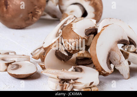 Frische Steinchampignons Champiggnons im ganzen und in Scheiben geschnitten auf einem weißen Holzbrett Foto Stock