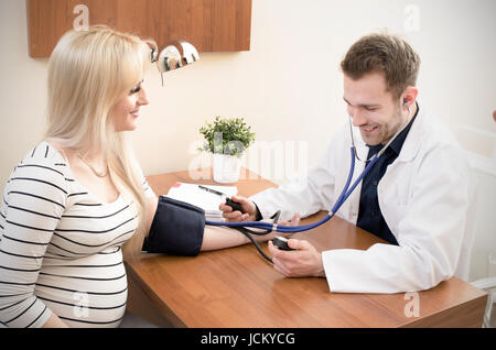 Giovane medico controllando la pressione del sangue del paziente femmina. La pressione del sangue del paziente medico medico sfigmomanometro di cuore il concetto di misurazione Foto Stock