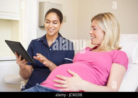 Infermiere con tavoletta digitale in riunione con donna in stato di gravidanza Foto Stock