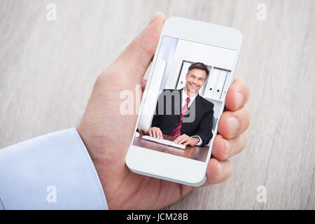 Immagine ritagliata di imprenditore videoconferenza con il collega alla scrivania Foto Stock