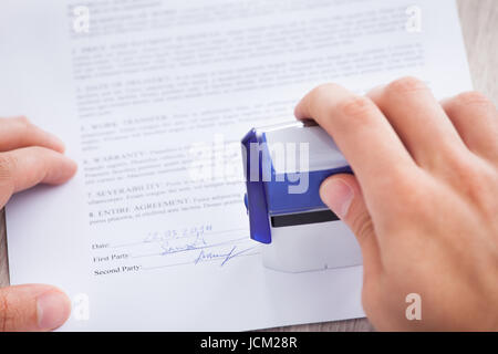 Immagine ritagliata di imprenditore di timbratura carta contratto sul tavolo Foto Stock