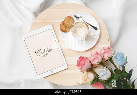 La prima colazione a letto con cappuccino, cookie e tablet Foto Stock