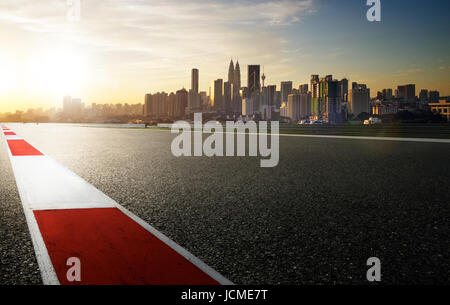 Autodromo con il rosso e bianco secondaria di sicurezza ,moderno sullo sfondo della città ,sunrise scena . Foto Stock