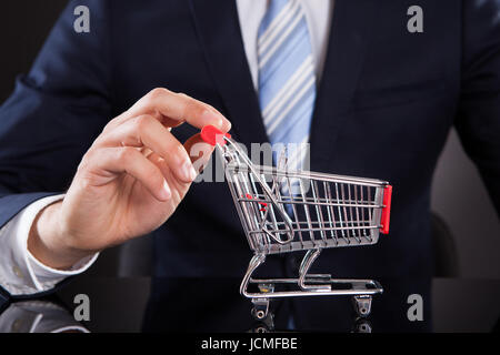 Sezione mediana di imprenditore con carrello modello alla scrivania Foto Stock