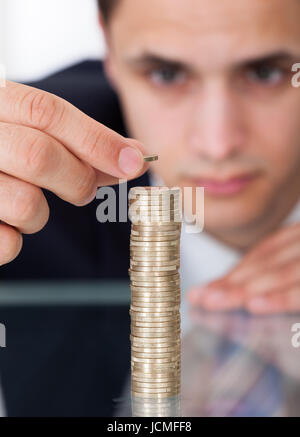 Primo piano di imprenditore di monete di stacking a scrivania in ufficio Foto Stock