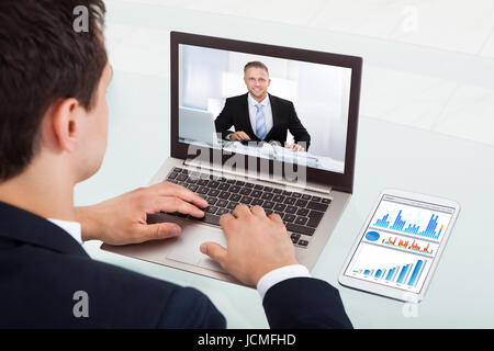 Immagine ritagliata del giovane imprenditore le videoconferenze su laptop alla scrivania in ufficio Foto Stock