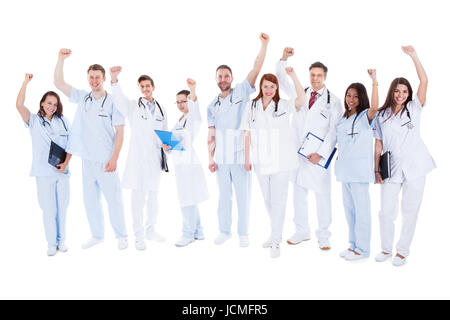 Diverse grandi società multietnica team medico in piedi il tifo e punzonatura l'aria con i loro pugni come si celebra un successo o motivare se stessi isolato su bianco Foto Stock