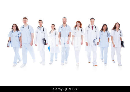 Grande variegato gruppo di medici e infermieri in uniforme a camminare verso la telecamera isolato su bianco Foto Stock