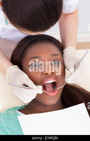 Angolo di Alta Vista del paziente di sesso femminile in fase di esame da parte del dentista in clinica Foto Stock