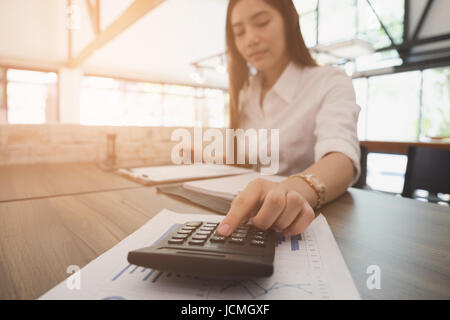 Asian imprenditrice utilizzando la calcolatrice al lavoro. giovane imprenditore femminile donna che lavorano con documenti aziendali in ufficio. analitica accou finanziario Foto Stock