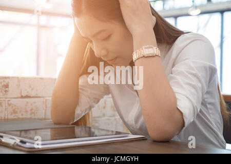 Giovane donna asiatica mettere mano sulla testa sensazione di stanchezza, frustrato e sottolineato dal duro lavoro mentre è seduto alla worklace in office Foto Stock