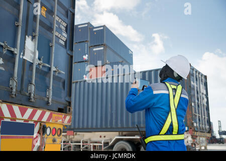 Il caporeparto di caricamento di controllo casella di contenitori da trasporto merce carrello per la logistica import export sfondo. Foto Stock