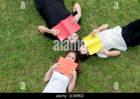 Top visuale globale gruppo di studenti asiatici che giace con i notebook e guardando lontano. Asian studente la preparazione per gli esami nel parco. Foto Stock