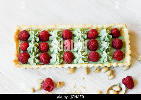 Crostata di pistacchio. Il pistacchio tart su bianco cioccolato Belga BARRY con uno strato di confettura di lamponi confit, croccante a base di pasta frolla e crema di fading e succosa raspb Foto Stock