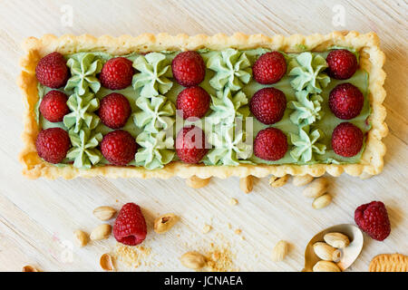 Crostata di pistacchio. Il pistacchio tart su bianco cioccolato Belga BARRY con uno strato di confettura di lamponi confit, croccante a base di pasta frolla e crema di fading e succosa raspb Foto Stock