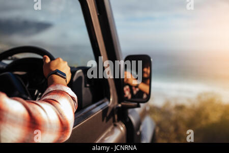 Immagine ritagliata dell uomo alla guida di auto. Focus sulla mano di un uomo con smart guarda sul volante del veicolo. Foto Stock