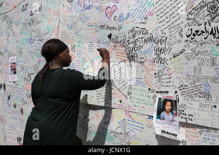 Londra, Regno Unito. 16 Giugno, 2017. Una donna che scrive un messaggio sulla parete del ricordo presso Latymer chiesa della Comunità per le vittime e i dispersi in seguito all'incendio che ha travolto il Grenfell torre a nord di Kensington. Credito: Mark Kerrison/Alamy Live News Foto Stock